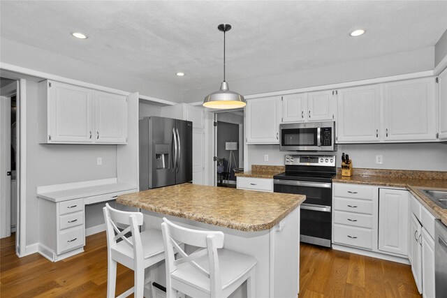 7422 Plum Dr, Urbandale, IA 50322 - kitchen with stainless steel appliances, dark wood-style flooring, white cabinetry, and recessed lighting