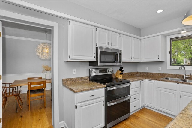 7422 Plum Dr, Urbandale, IA 50322 - kitchen with appliances with stainless steel finishes, a sink, light wood-style floors, white cabinets, and recessed lighting