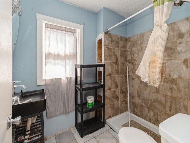 full bathroom with toilet, tiled shower, and tile patterned flooring