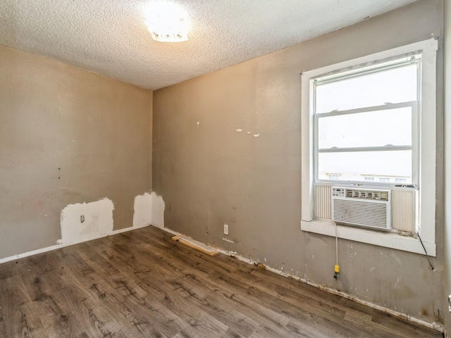 unfurnished room with wood finished floors, cooling unit, and a textured ceiling