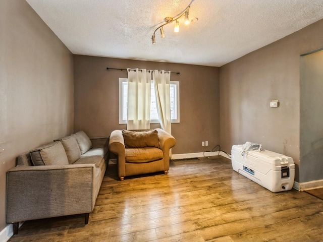 sitting room with wood finished floors, a textured ceiling, and baseboards