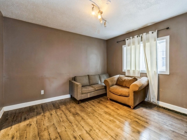 living room featuring a textured ceiling, light wood-style floors, and baseboards