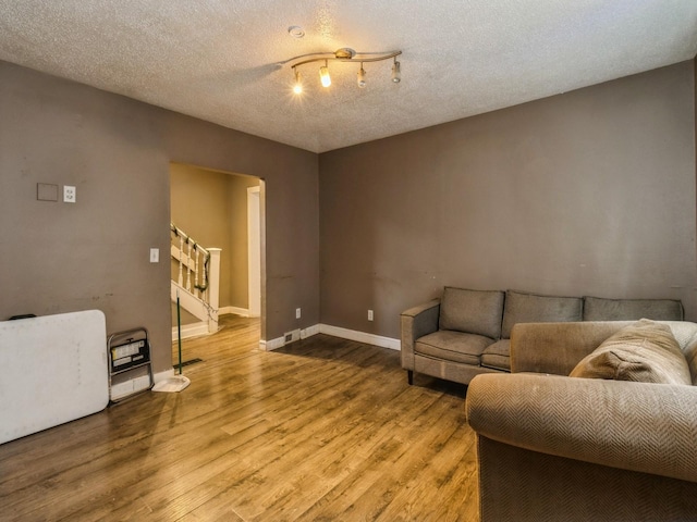 living area featuring wood finished floors, a textured ceiling, and baseboards