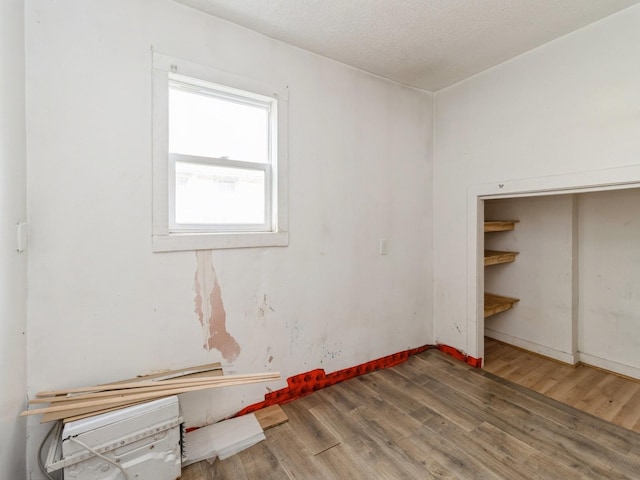 unfurnished bedroom with wood finished floors, baseboards, and a closet