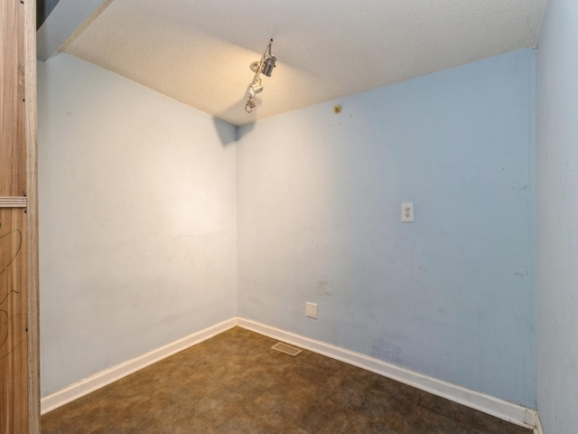 unfurnished room featuring a textured ceiling and baseboards