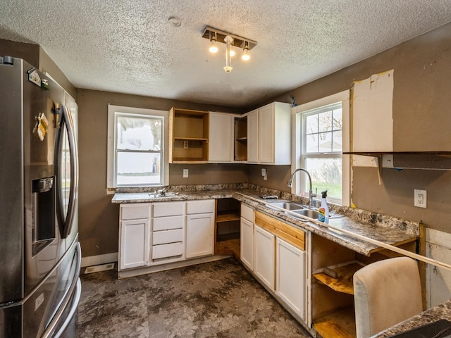 kitchen with stainless steel refrigerator with ice dispenser, open shelves, a textured ceiling, a sink, and white cabinetry
