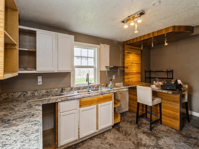 kitchen featuring a sink, open shelves, white cabinetry, and a textured ceiling