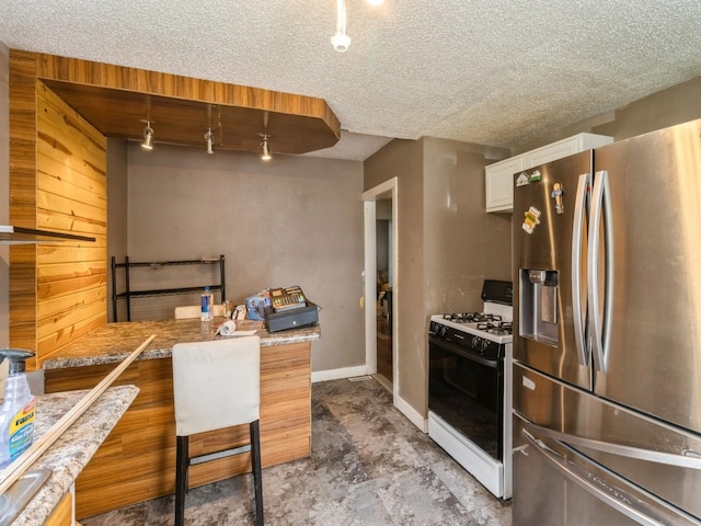 kitchen with stainless steel refrigerator with ice dispenser, gas stove, a textured ceiling, and white cabinets