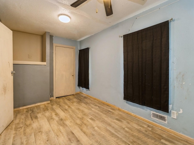 spare room with a ceiling fan, wood finished floors, a textured ceiling, and baseboards