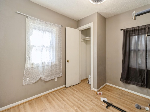 unfurnished bedroom featuring wood finished floors, baseboards, and a textured ceiling
