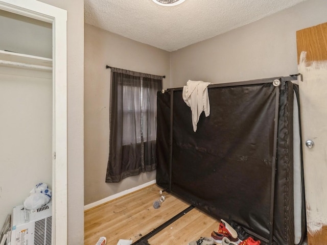 bedroom featuring wood finished floors, a textured ceiling, and baseboards