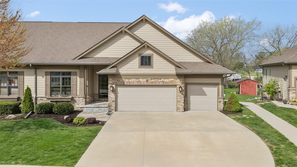 craftsman inspired home featuring stone siding, concrete driveway, a front lawn, roof with shingles, and a garage