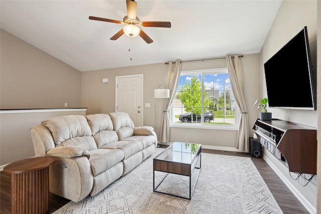 living area featuring ceiling fan, wood finished floors, baseboards, and vaulted ceiling
