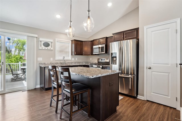 kitchen with stainless steel appliances, dark brown cabinetry, vaulted ceiling, a center island, and a breakfast bar