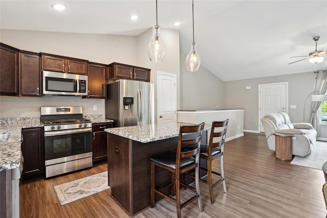 kitchen with stainless steel appliances, dark brown cabinetry, open floor plan, wood finished floors, and ceiling fan