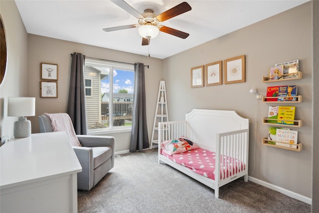 bedroom featuring carpet flooring, a crib, baseboards, and a ceiling fan