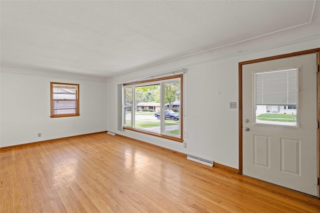 unfurnished room with light wood finished floors, baseboards, a baseboard heating unit, and a textured ceiling