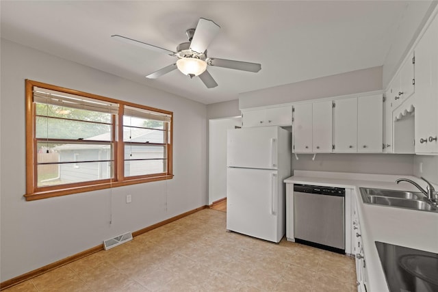 kitchen featuring freestanding refrigerator, stainless steel dishwasher, a sink, light countertops, and white cabinetry