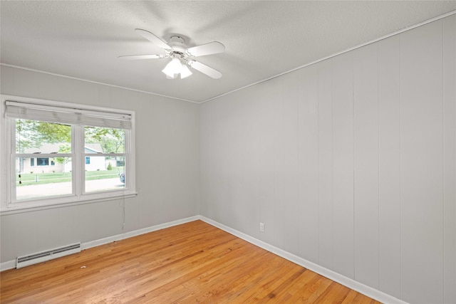 empty room featuring a baseboard radiator, light wood-type flooring, a ceiling fan, a textured ceiling, and baseboards