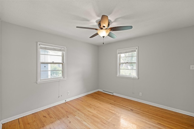 empty room featuring light wood-style flooring, baseboards, ceiling fan, and a baseboard heating unit