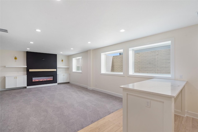 3943 NW 181st St, Clive, IA 50325 - unfurnished living room featuring a glass covered fireplace, baseboards, light wood finished floors, recessed lighting, and light carpet