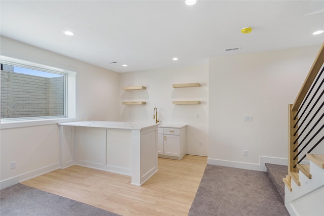 3943 NW 181st St, Clive, IA 50325 - kitchen featuring open shelves, light wood-style flooring, a peninsula, recessed lighting, and a sink