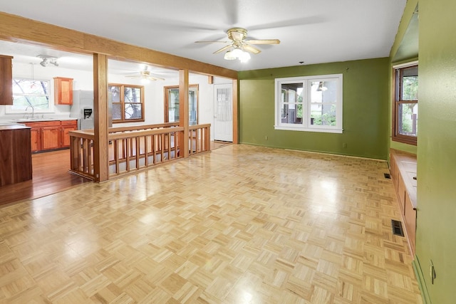 2226 Idaho Dr, Pella, IA 50219 - unfurnished living room featuring ceiling fan, baseboards, and a sink