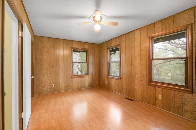 2226 Idaho Dr, Pella, IA 50219 - spare room with light wood-style flooring, a ceiling fan, and wooden walls