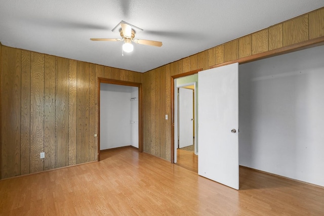 2226 Idaho Dr, Pella, IA 50219 - empty room with a ceiling fan, light wood-type flooring, and wood walls