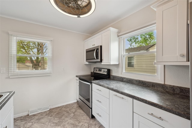 2012 61st St, Des Moines, IA 50322 - kitchen with stainless steel appliances, crown molding, dark countertops, baseboards, and white cabinets