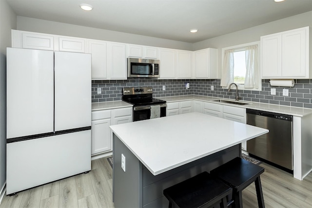 1001 Willow Valley Dr, Norwalk, IA 50211 - kitchen with appliances with stainless steel finishes, a sink, light wood-style floors, a kitchen breakfast bar, and recessed lighting
