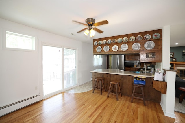 541 S Cedar St, Boone, IA 50036 - kitchen featuring baseboard heating, a peninsula, a sink, freestanding refrigerator, and light wood-type flooring