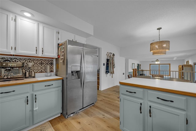 kitchen featuring stainless steel fridge with ice dispenser, light wood-style flooring, tasteful backsplash, light countertops, and pendant lighting