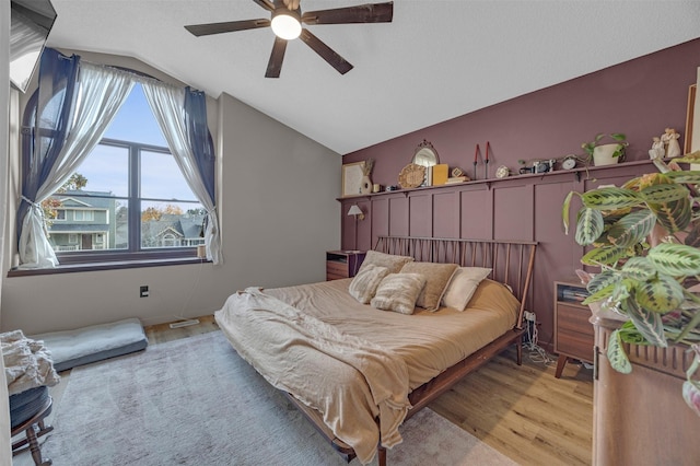 bedroom featuring lofted ceiling, light wood-style flooring, and a ceiling fan