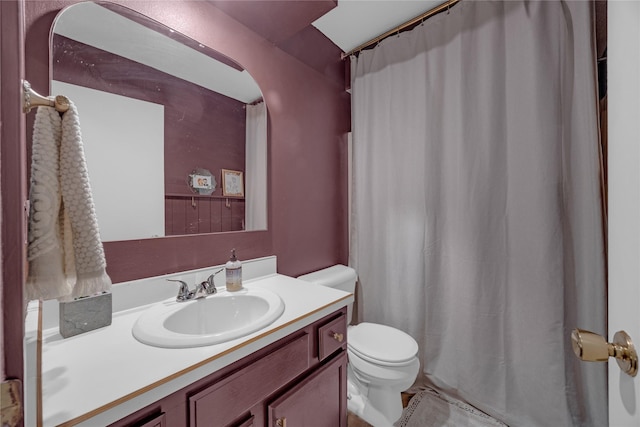 bathroom featuring toilet, vanity, and curtained shower