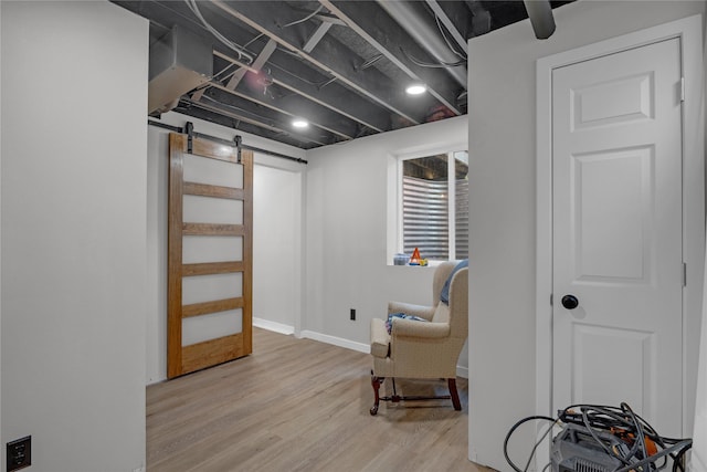finished below grade area featuring wood finished floors, a barn door, and baseboards