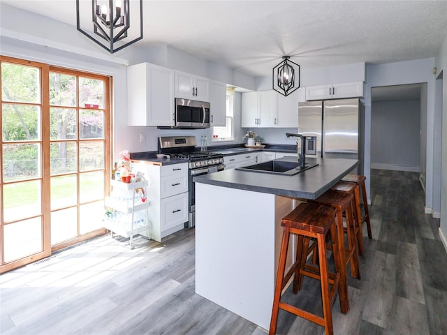 kitchen with stainless steel appliances, a sink, dark countertops, and plenty of natural light