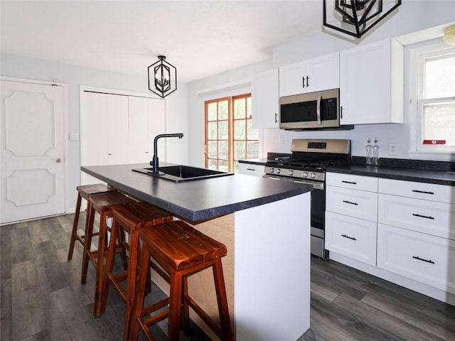 kitchen featuring appliances with stainless steel finishes, a sink, dark countertops, and healthy amount of natural light