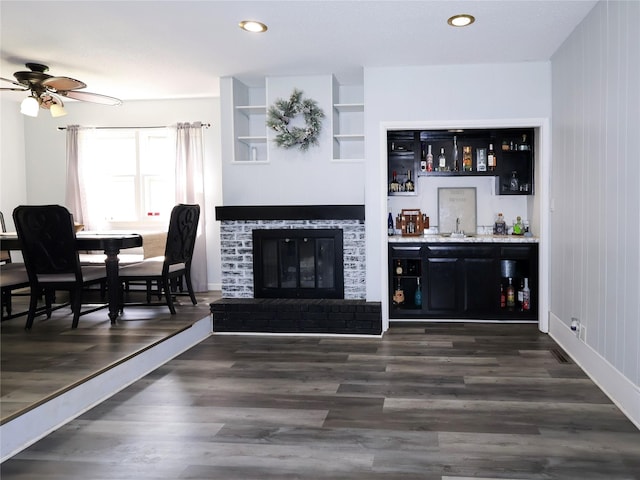living room with a bar, ceiling fan, dark wood-style flooring, recessed lighting, and a fireplace