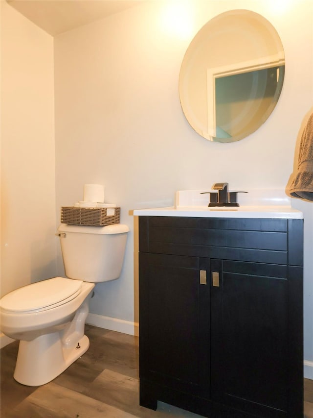 bathroom with wood finished floors, toilet, baseboards, and vanity