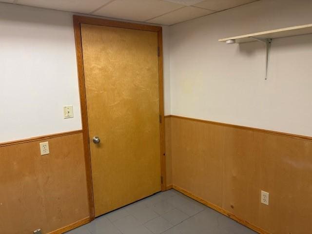 1604 Elder Dr, Marshalltown, IA 50158 - spare room featuring a wainscoted wall, wooden walls, and a drop ceiling