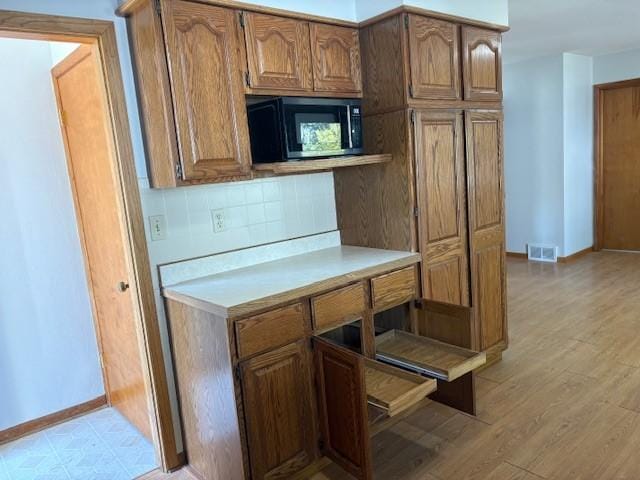 1604 Elder Dr, Marshalltown, IA 50158 - kitchen featuring decorative backsplash, baseboards, light countertops, and brown cabinets