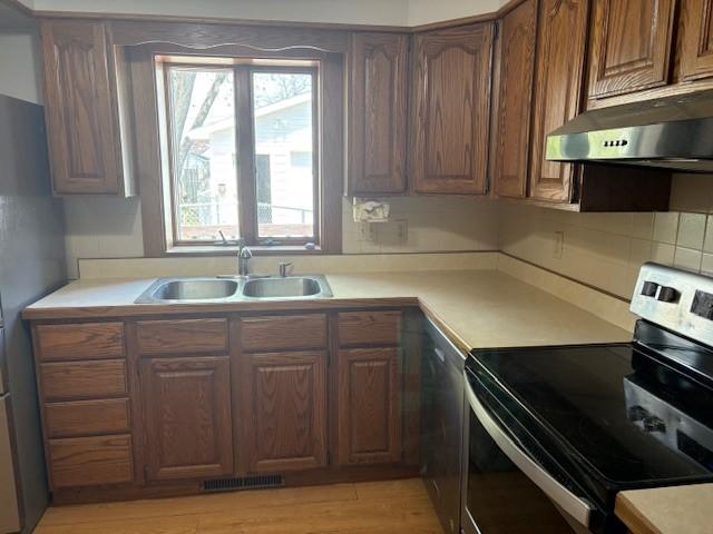 1604 Elder Dr, Marshalltown, IA 50158 - kitchen with appliances with stainless steel finishes, under cabinet range hood, a sink, and light countertops