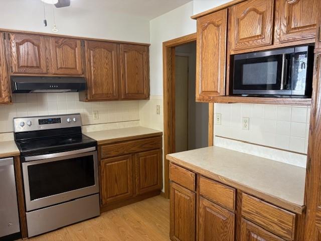 1604 Elder Dr, Marshalltown, IA 50158 - kitchen featuring stainless steel electric range, under cabinet range hood, black microwave, light countertops, and light wood-type flooring