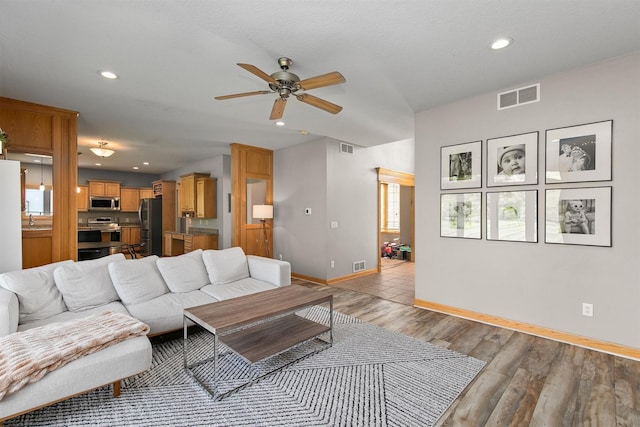 living room featuring ceiling fan, baseboards, recessed lighting, and light wood-style flooring