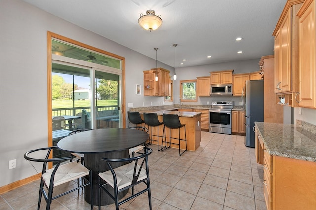 kitchen with appliances with stainless steel finishes, a peninsula, light tile patterned flooring, plenty of natural light, and recessed lighting