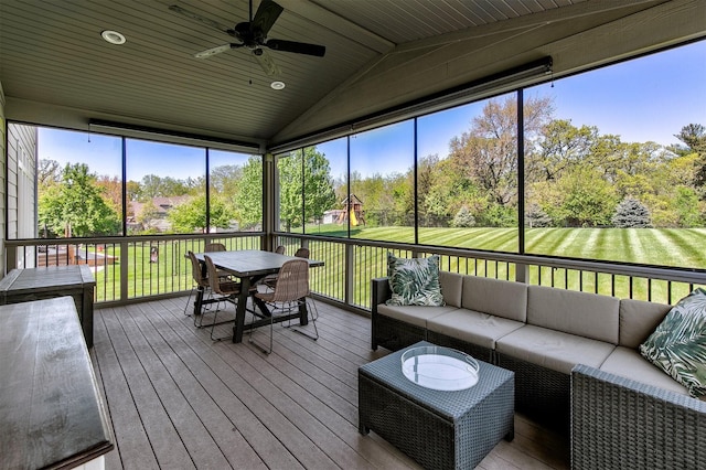 sunroom featuring an outdoor living space, outdoor dining area, a ceiling fan, vaulted ceiling, and view of scattered trees