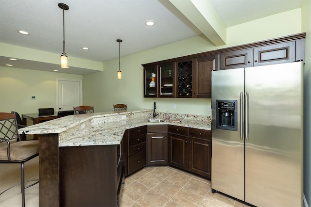 1914 Park Ave, Des Moines, IA 50315 - kitchen with stainless steel fridge, a kitchen breakfast bar, a peninsula, dark brown cabinets, and recessed lighting