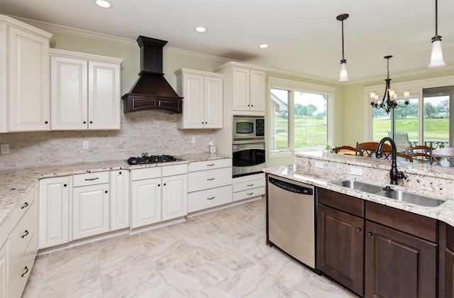 1914 Park Ave, Des Moines, IA 50315 - kitchen featuring appliances with stainless steel finishes, custom range hood, crown molding, dark brown cabinetry, and a chandelier