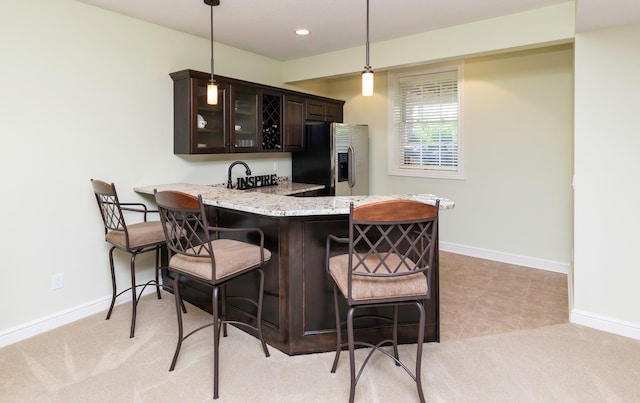 1914 Park Ave, Des Moines, IA 50315 - kitchen with stainless steel fridge, dark brown cabinetry, a breakfast bar, a peninsula, and glass insert cabinets